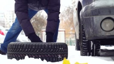  Adam eski bir araba yakınındaki kar lastikleri yeni bir dizi istifleme
