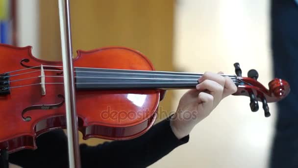 Молодая девушка играет на скрипке в школьном коридоре — стоковое видео