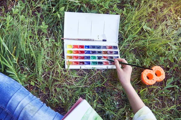 Junges Mädchen malt im Sommer auf Gras sitzend — Stockfoto