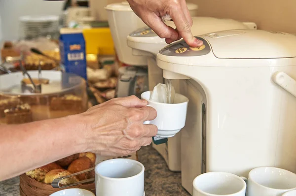 Woman brewing a tea from thermo pot in hotel kitchen — Stock Photo, Image