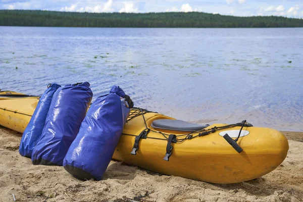 Waterproof bags standing by yellow plastic kayak — Stock Photo, Image