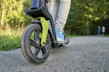 Kız asfalt yolda kick scooter üzerinde sürme