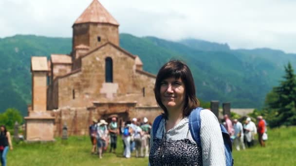 Mujer turista sonriente frente a la antigua iglesia armenia en verano — Vídeo de stock