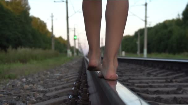 Tiener meisje lopen op blote voeten langs de spoorweg spoor — Stockvideo