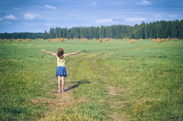Mädchen steht mit erhobenen Händen auf dem Feld — Stockfoto