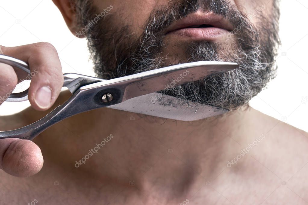 Middle-aged man cuts his beard using big scissors