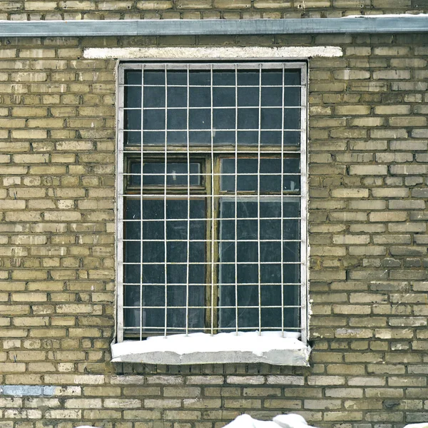 Решетка на окне старого советского кирпичного дома — стоковое фото