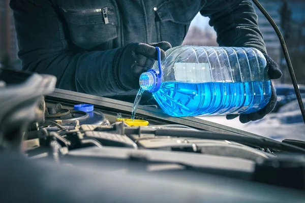 Homem derramando um líquido anticongelante em um tanque de lava pára-brisas de um carro — Fotografia de Stock