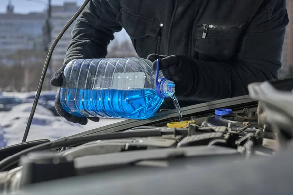 Mann füllt Scheibenwaschbecken eines Autos mit Frostschutzmittel — Stockfoto