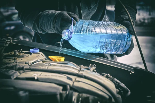 Muž lití nemrznoucí kapaliny v nádrži ostřikovače čelního skla automobilu — Stock fotografie