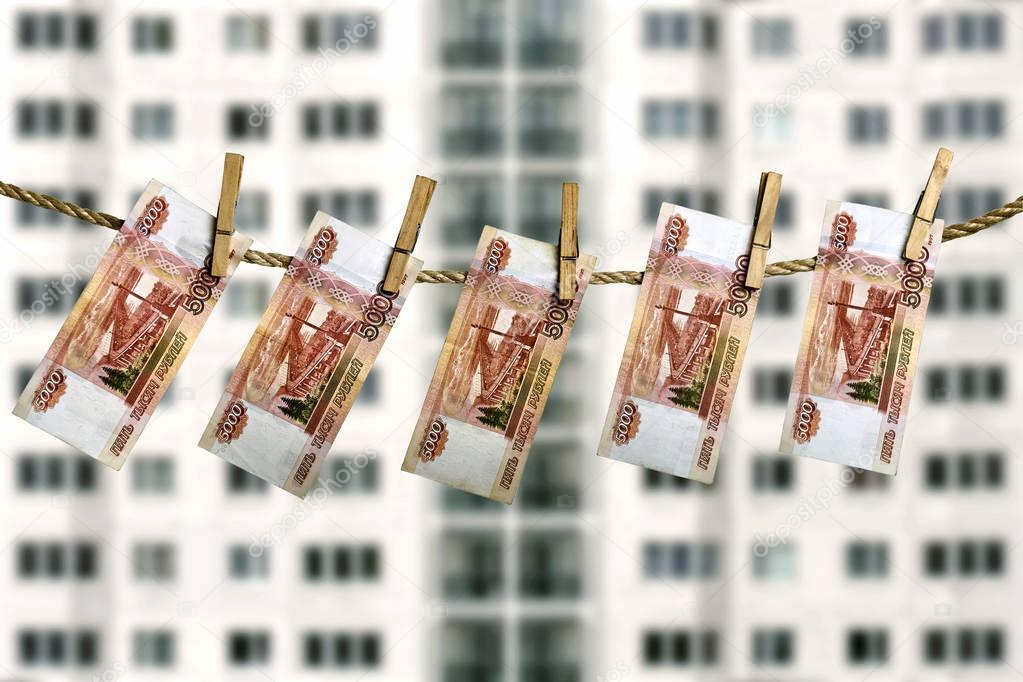 Russian rouble banknotes hanging on a clothesline on the blurred facade of a dwelling house background.