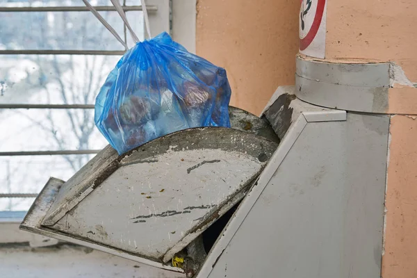 Garbage bag full of a garbage lying in a lid of a home garbage chute