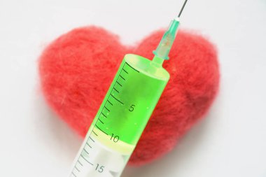 Kırmızı kalpte yeşil bir ilaç bulunan bir şırınga.