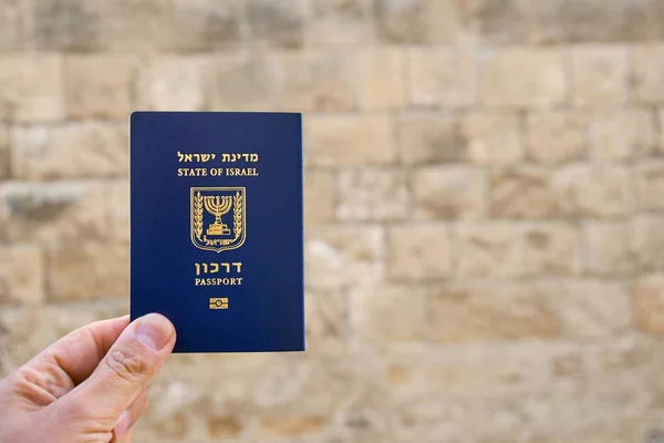 Male hand holds an Israel passport with ancient wall of old Jaffa