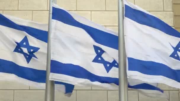 3つのイスラエル国旗が屋外の壁の前で風に手を振って閉じます 4K解像度ビデオ — ストック動画