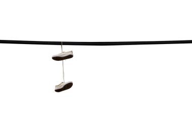 Shoes hang on an electric wire on the street of the city isolated on white clipart