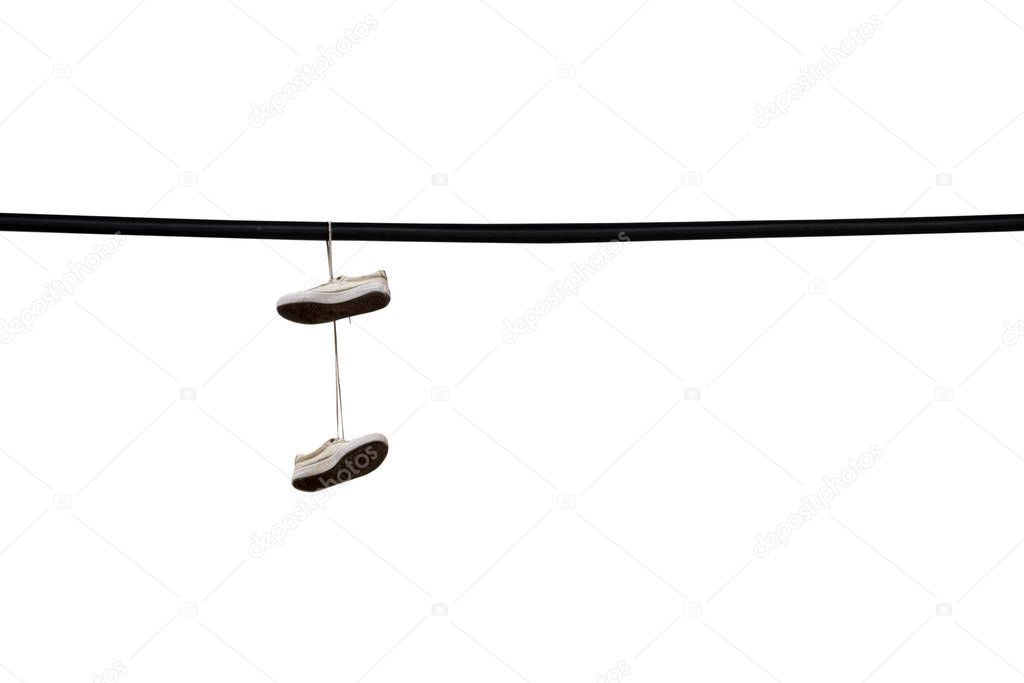 Shoes hang on an electric wire on the street of the city isolated on white