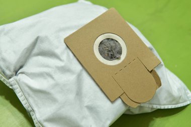 Çamur ve çöp dolu kullanılmış bir kum torbası yeşil yüzeye yakın duruyor.