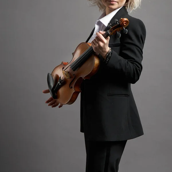 Young woman violinist in a black male suit with a violin