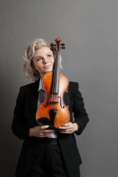 Portrait of an young woman violinist in a black male suit with a violin looking up — Stock Photo, Image