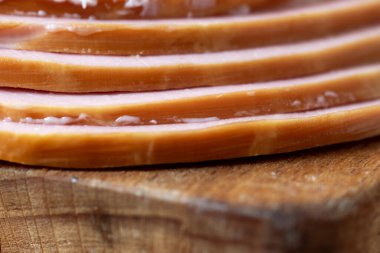 Tahta kesme tahtasının üzerinde duran lezzetli haşlanmış sosis dilimleri. Dilimlenmiş lezzetli sosis yakın plan.