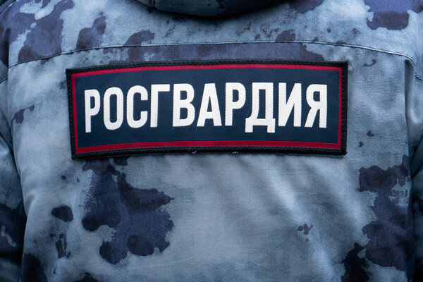 Back of a soldier of Russian Guard wearing military camouflage uniform with label Russian Guard