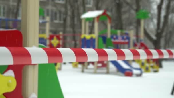 風に揺れるバリアテープは モスクワのコロナウイルスCovid 19の隔離中に雪で覆われた空の子供の遊び場への入り口を禁止 — ストック動画