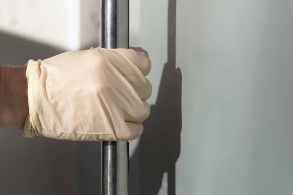 Hand i en skyddshandske för att förhindra infektion med coronavirus öppnar dörren med metallhandtaget — Stockfoto