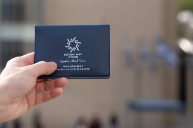 Kadın eli İsrail 'in arka planına karşılık geçici bir İsrail pasaportu tutuyor.