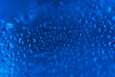 Mavi cam arka planda su damlaları var. Sığ alan derinliği
