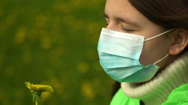 Teenagermädchen in medizinischer Schutzmaske erschnüffelt gelben Löwenzahn aus nächster Nähe — Stockvideo