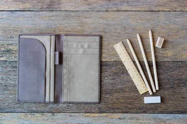 Öppen bok som täcker trä bakgrund med pennor och linjal. — Stockfoto
