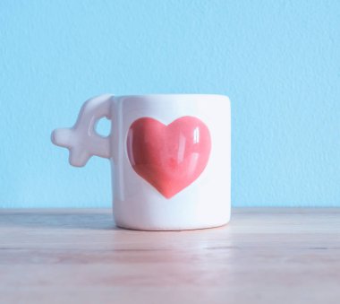 Beyaz seramik kahve fincanı ahşap masa üzerinde pembe kalpli bir