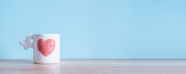 Beyaz seramik kahve fincanı ahşap masa üzerinde pembe kalpli bir