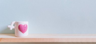 Beyaz seramik kahve fincanı ahşap masa üzerinde pembe kalpli bir