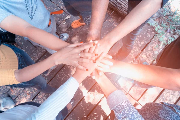 İş ekibi el ele verip güneş ışığı ve mercek parlaması ile daire içine alınmış bir grup insana katılıyor. * Konseptler takım oluşturur ve başarı için projeler yapar..