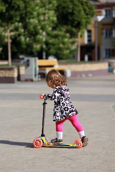 Nettes kleines Mädchen auf einem Motorroller im Sommerpark — Stockfoto