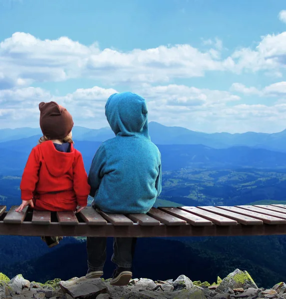 Twee kinderen zitten op een bankje en het bewonderen van het landschap van bergen — Stockfoto