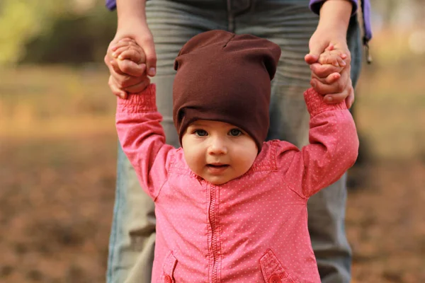 Retrato de um bebê bonito menina segurando as mãos da mãe e aprender a andar — Fotografia de Stock