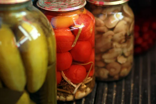Rad av burkar med inlagda tomater, cucmbers och champinjoner — Stockfoto