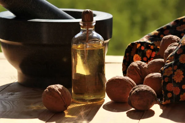 Malty, rozptýlené ořechů a láhev oleje proti rozmazané pozadí zelené zátiší — Stock fotografie