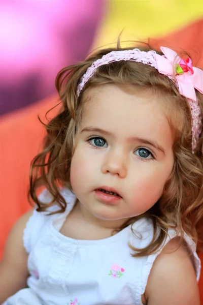 Doce menina de um ano de idade contra fundo colorido brilhante borrado — Fotografia de Stock