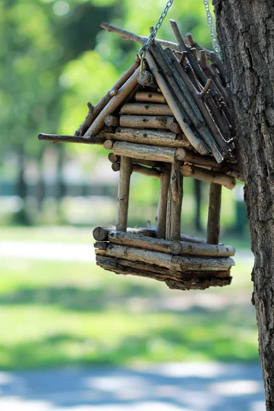 Casa de pássaro de madeira feita à mão criativa / alimentador de pássaros pendurado em uma corrente na árvore em um parque — Fotografia de Stock