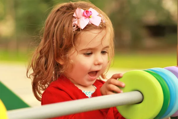 Happy one year old girl playing with wooden colorful circles