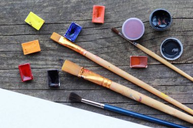 Uo kaba gri ahşap masa doku düz renkli ve suluboya Akrilik boyalar yerleşimini, fırçalar ve ilişkili beyaz albüm sayfasını dizi alay