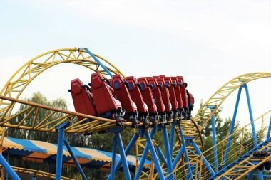 Kırmızı rollercoaster eğlence parkı içinde mavi gökyüzü mavi ve sarı demiryolu sürme