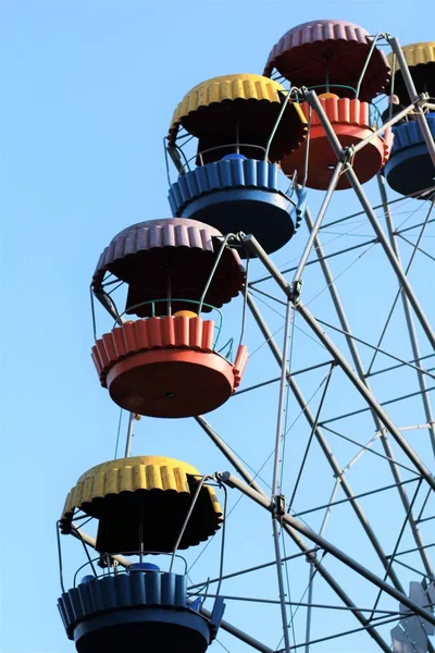 Rueda de ferris de colores que se mueve contra el cielo azul en el parque de atracciones de verano —  Fotos de Stock