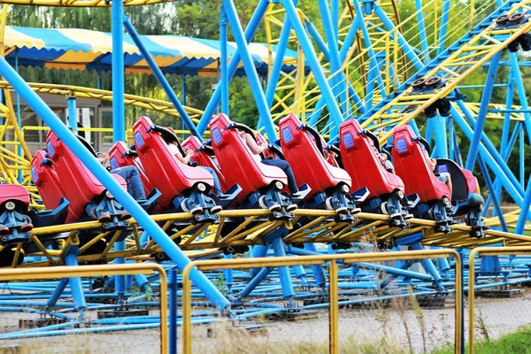 Kırmızı rollercoaster eğlence parkı içinde mavi gökyüzü mavi ve sarı demiryolu sürme — Stok fotoğraf