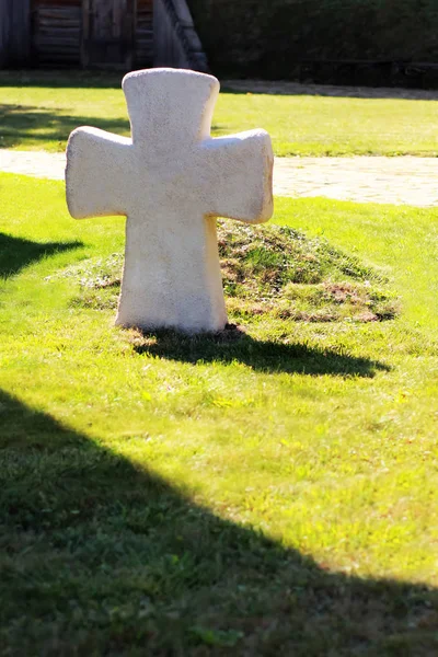 Croix blanche pierre tombale sur la pelouse verte avec son ombre — Photo