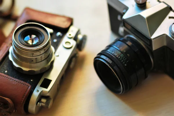 Due vecchie fotocamere vintage su un tavolo marrone chiaro. Uno in pelle retrò marrone custodia titolare — Foto Stock